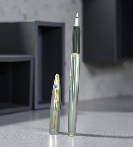 Two pens, one silver and one gold, on a reflective surface with a blurred background.