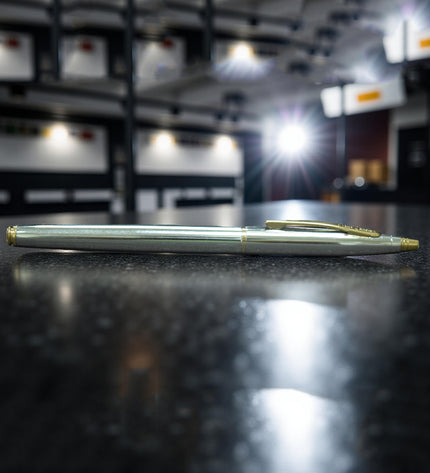 Silver pen on a reflective surface with a blurred indoor setting