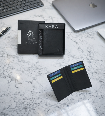 Black Kara wallet on a marble surface with packaging and office items in the background