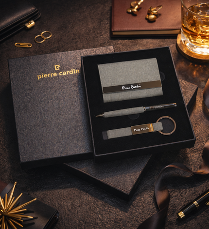 Pierre Cardin business card holder set with pen and keychain on a dark surface.