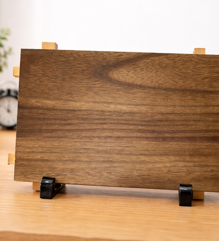 Wooden photo frame on a desk with books and plants in the background