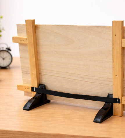 Wooden photo frame stand on a desk with books and plants in the background