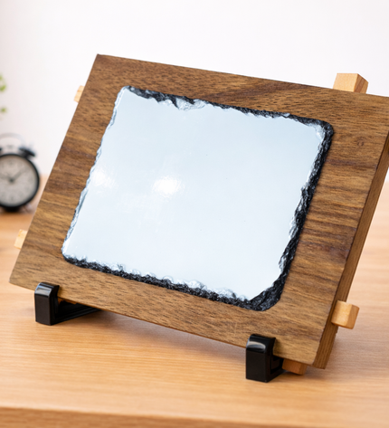 Wooden frame with a glass panel on a desk with books and plants in the background