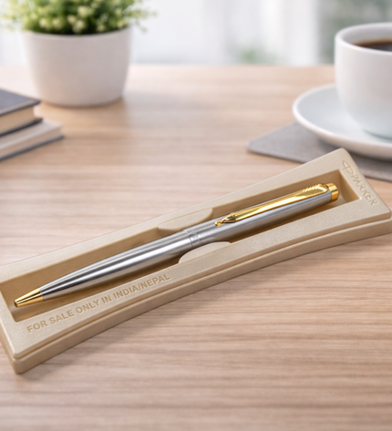 Silver pen in a gold box on a desk with a cup of coffee and stationery items.