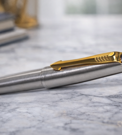 Close-up of a silver pen with gold accents on a marble surface