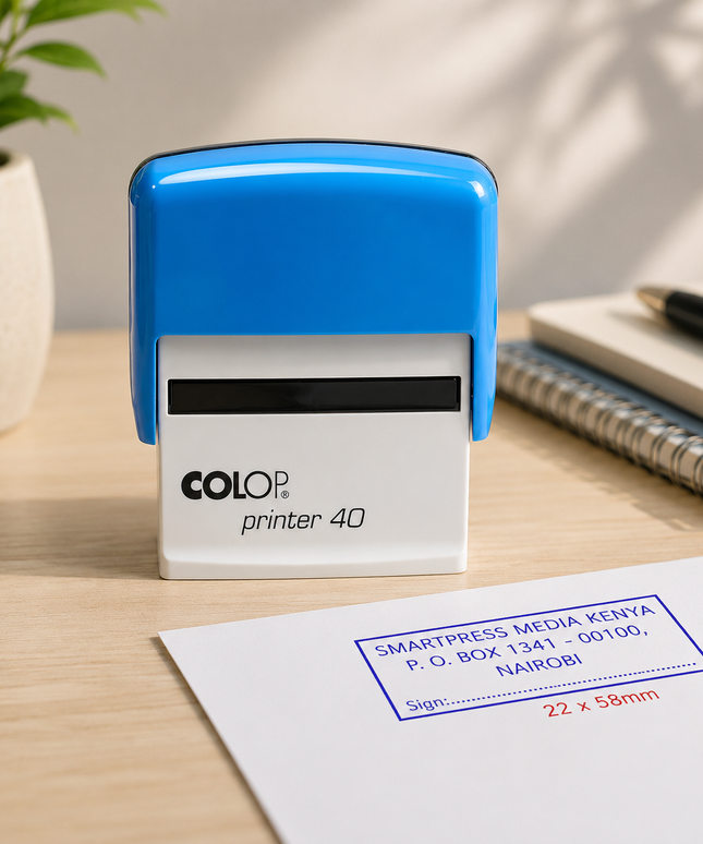 Colop printer 40 stamp on a desk with a plant and notebook in the background