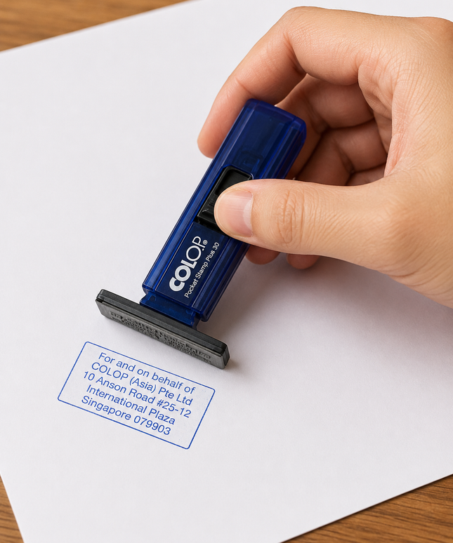 Hand using a Colop stamp on a piece of paper