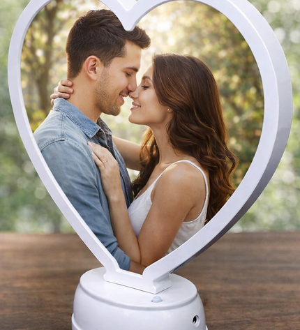 Heart-shaped photo frame with a couple embracing inside, placed on a wooden surface.